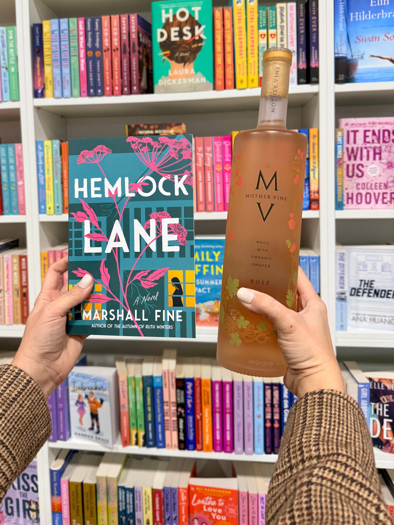 Person holding a book with a colorful shelf of books in the background